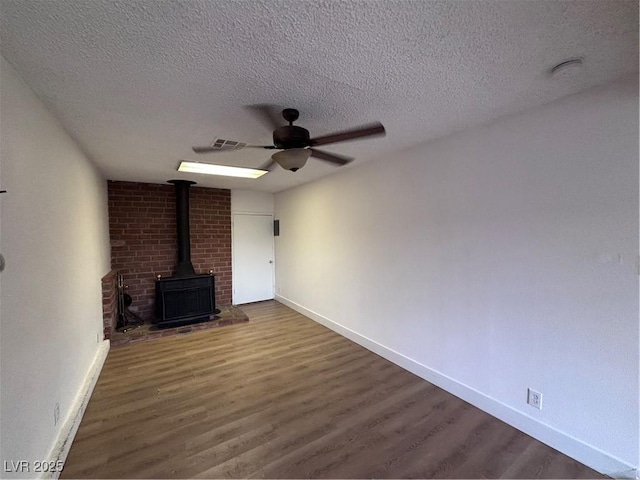 5920 Glen Eagles Ln, Las Vegas, NV 89108 - unfurnished living room featuring a wood stove, baseboards, wood finished floors, and a textured ceiling