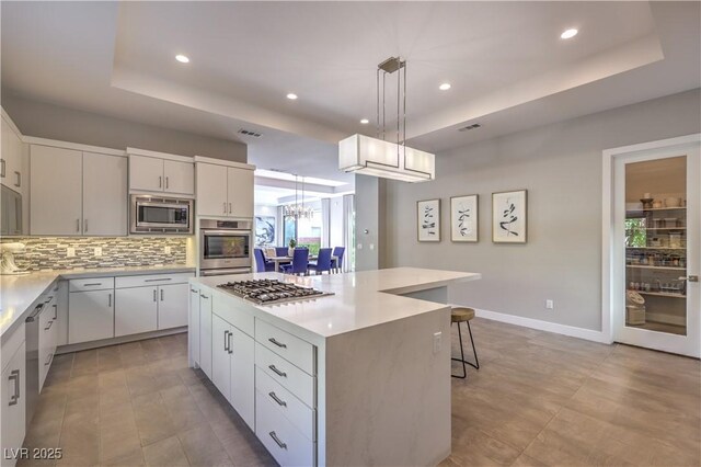 10 Sugarberry Ln, Las Vegas, NV 89135 - kitchen featuring appliances with stainless steel finishes, a raised ceiling, a center island, recessed lighting, and tasteful backsplash