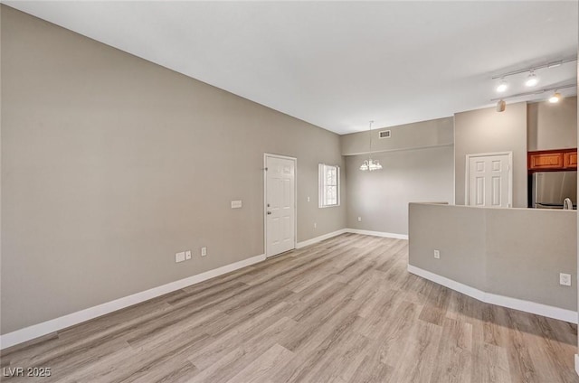 9303 Gilcrease Ave Unit 2217, Las Vegas, NV 89149 - unfurnished living room featuring light wood-style floors, baseboards, a chandelier, and rail lighting