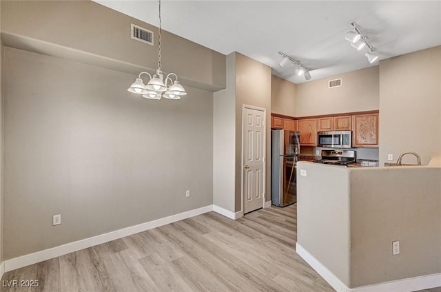 9303 Gilcrease Ave Unit 2217, Las Vegas, NV 89149 - kitchen with stainless steel appliances, track lighting, light wood-style flooring, baseboards, and decorative light fixtures