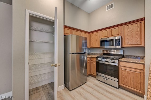 9303 Gilcrease Ave Unit 2217, Las Vegas, NV 89149 - kitchen with appliances with stainless steel finishes, light wood finished floors, and light stone counters
