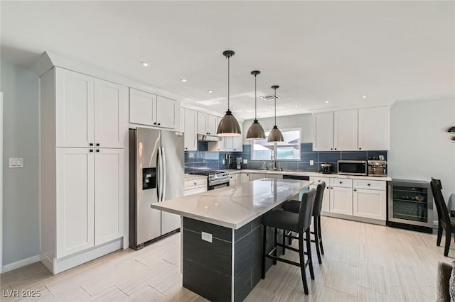 6309 Miraloma St, Las Vegas, NV 89108 - kitchen featuring appliances with stainless steel finishes, beverage cooler, tasteful backsplash, white cabinetry, and recessed lighting