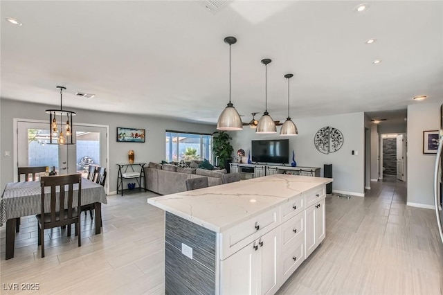 6309 Miraloma St, Las Vegas, NV 89108 - kitchen with a center island, baseboards, a chandelier, white cabinets, and light stone counters