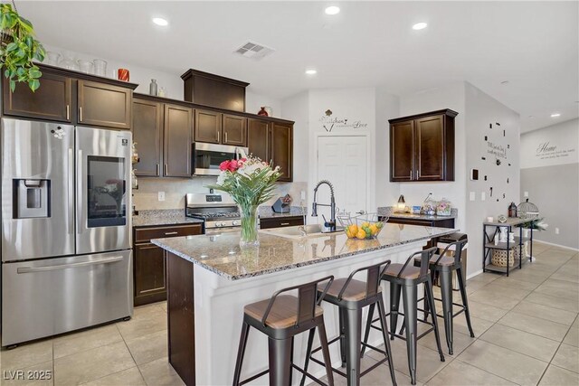 2169 Rio Rancho Pointe Pl, Henderson, NV 89002 - kitchen with appliances with stainless steel finishes, light tile patterned floors, a sink, dark brown cabinets, and recessed lighting
