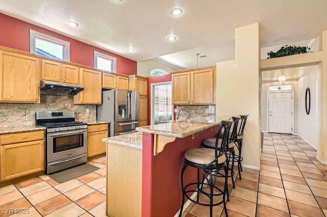 8777 Shady Peak Way, Las Vegas, NV 89123 - kitchen with stainless steel appliances, under cabinet range hood, a peninsula, a kitchen breakfast bar, and decorative backsplash