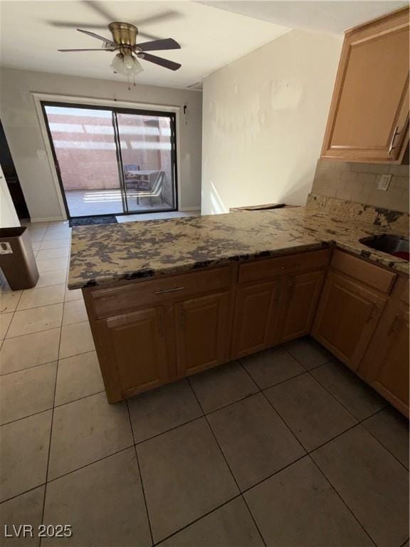 6521 Sugarpine Ln, Las Vegas, NV 89107 - kitchen featuring a peninsula, a ceiling fan, light stone countertops, light tile patterned flooring, and backsplash