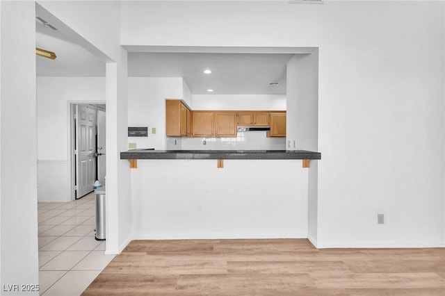 1951 Moyer Dr, Henderson, NV 89074 - kitchen featuring dark countertops, a breakfast bar area, under cabinet range hood, a peninsula, and recessed lighting