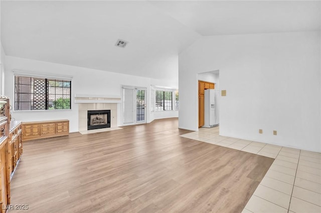 1951 Moyer Dr, Henderson, NV 89074 - unfurnished living room featuring light wood-style floors, a tiled fireplace, and high vaulted ceiling