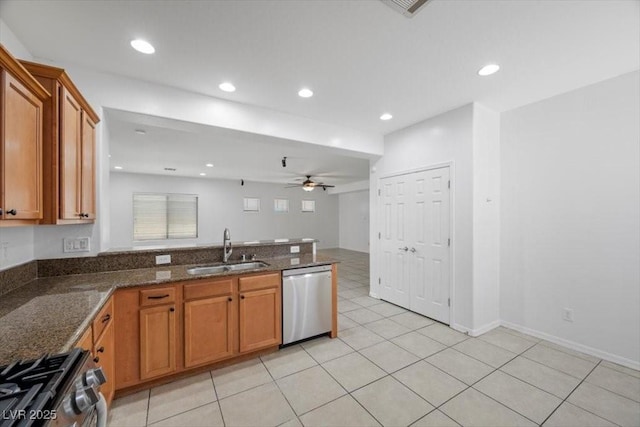 4062 Vulcan St, Las Vegas, NV 89122 - kitchen featuring appliances with stainless steel finishes, brown cabinets, a peninsula, a ceiling fan, and dark stone countertops