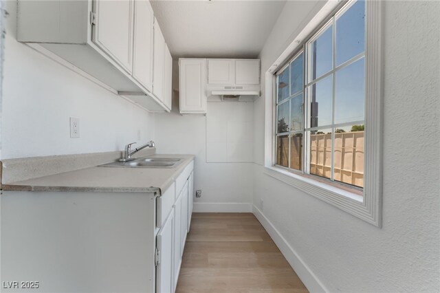 517 N 22nd St, Las Vegas, NV 89101 - kitchen with baseboards, a sink, white cabinetry, light wood-style floors, and light countertops