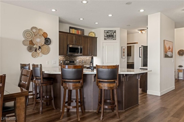 1309 Vista Del Monte Dr, Mesquite, NV 89027 - kitchen with stainless steel microwave, light countertops, dark wood-style floors, a peninsula, and recessed lighting