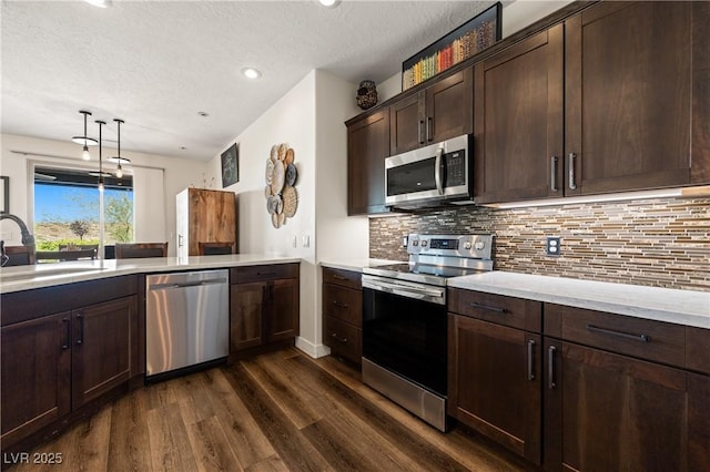 1309 Vista Del Monte Dr, Mesquite, NV 89027 - kitchen featuring appliances with stainless steel finishes, a sink, dark wood finished floors, dark brown cabinetry, and decorative backsplash