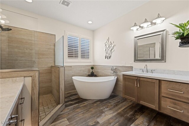 1309 Vista Del Monte Dr, Mesquite, NV 89027 - bathroom featuring vanity, a walk in shower, a soaking tub, wood finished floors, and tile walls