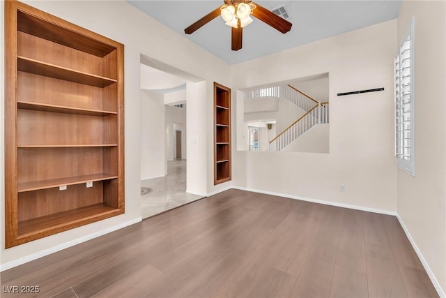 1155 Phillip Island St, Henderson, NV 89052 - unfurnished living room with ceiling fan, built in shelves, stairs, and wood finished floors