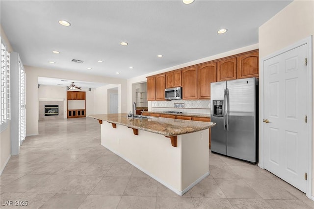 1155 Phillip Island St, Henderson, NV 89052 - kitchen featuring appliances with stainless steel finishes, ceiling fan, light stone countertops, a kitchen bar, and decorative backsplash