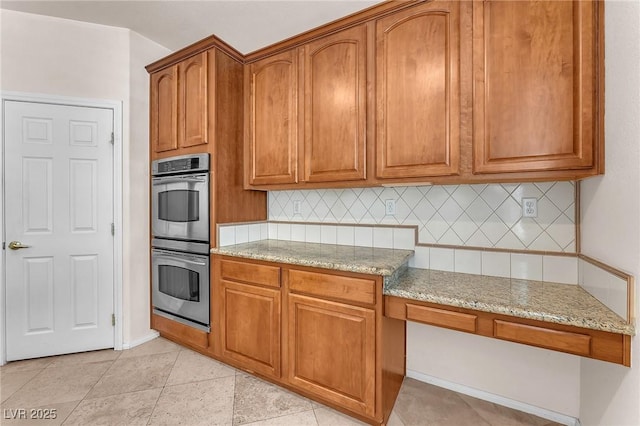 1155 Phillip Island St, Henderson, NV 89052 - kitchen featuring double oven, backsplash, light stone counters, and brown cabinetry