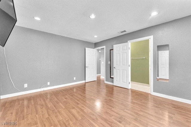 5012 Newport Cove Dr Unit C, Las Vegas, NV 89119 - unfurnished bedroom with light wood-style floors, baseboards, recessed lighting, a walk in closet, and a textured wall