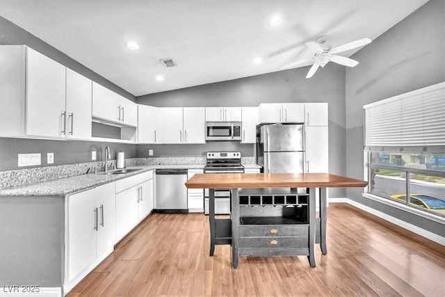 5012 Newport Cove Dr Unit C, Las Vegas, NV 89119 - kitchen with stainless steel appliances, a sink, light wood-type flooring, white cabinetry, and high vaulted ceiling