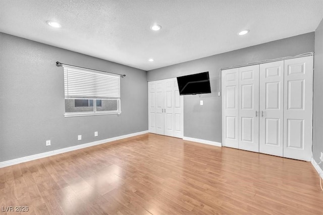 5012 Newport Cove Dr Unit C, Las Vegas, NV 89119 - unfurnished bedroom with multiple closets, light wood finished floors, baseboards, recessed lighting, and a textured ceiling