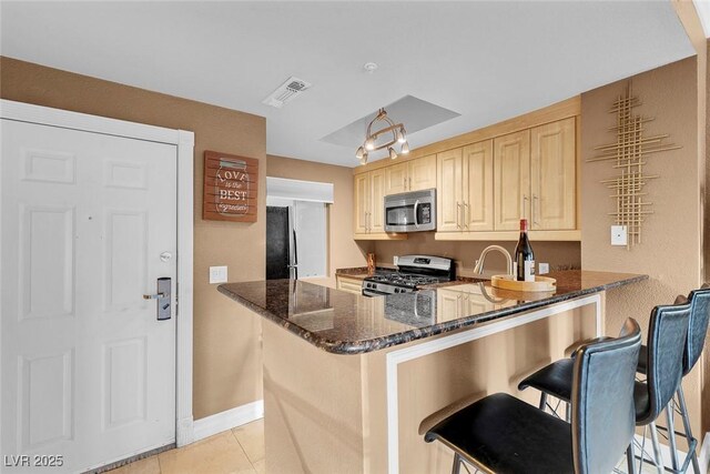 270 E Flamingo Rd Unit 131, Las Vegas, NV 89169 - kitchen with appliances with stainless steel finishes, dark stone counters, light tile patterned floors, baseboards, and a breakfast bar area