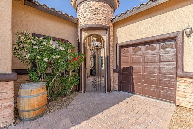5576 Buena Martina Way, Las Vegas, NV 89141 - view of exterior entry with stucco siding, an attached garage, a gate, stone siding, and driveway
