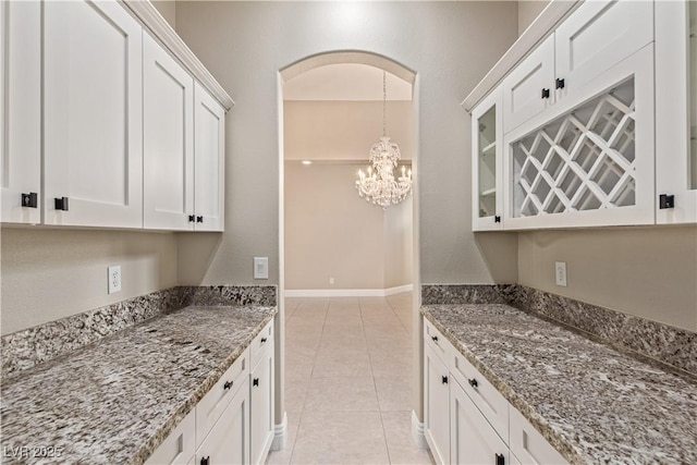 5576 Buena Martina Way, Las Vegas, NV 89141 - kitchen featuring white cabinets, a chandelier, light stone countertops, arched walkways, and light tile patterned floors