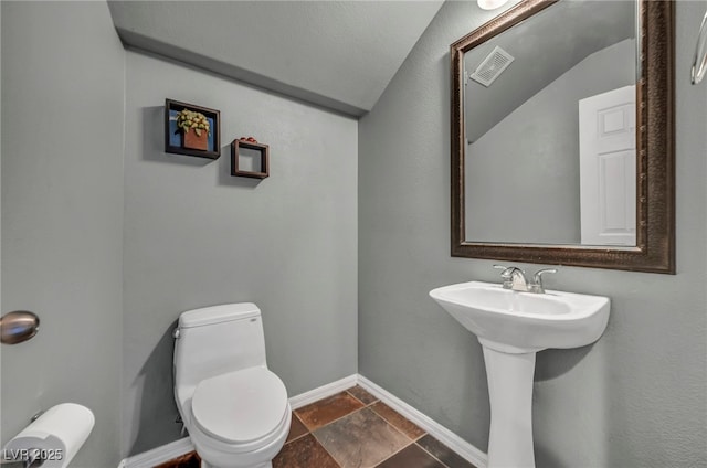 2449 Daks Loden Ct, Henderson, NV 89044 - bathroom featuring lofted ceiling, toilet, baseboards, and stone finish flooring