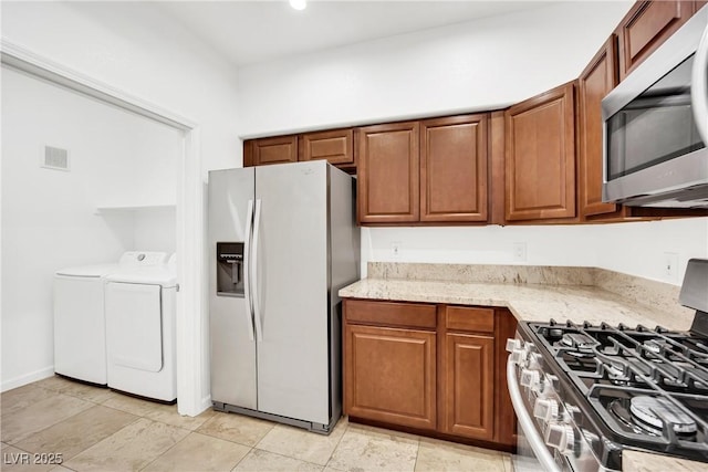8725 W Flamingo Rd Unit 110, Las Vegas, NV 89147 - kitchen featuring stainless steel appliances, washing machine and clothes dryer, light stone countertops, and brown cabinetry