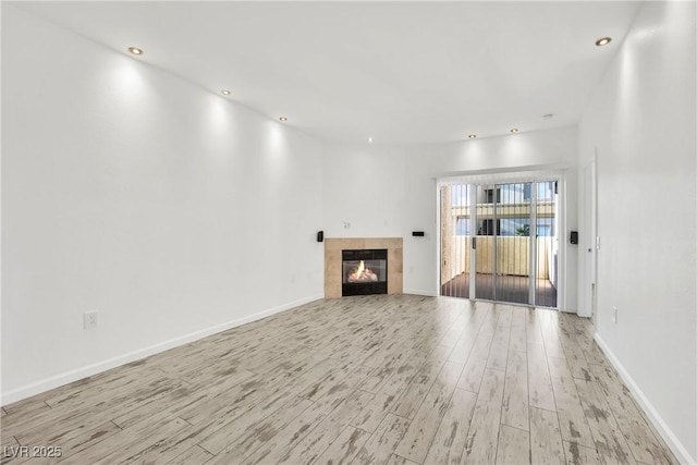 8725 W Flamingo Rd Unit 110, Las Vegas, NV 89147 - unfurnished living room featuring light wood-style floors, a tiled fireplace, baseboards, and recessed lighting