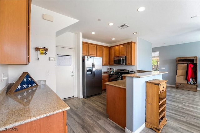 6121 Mission Gorge Ct, Las Vegas, NV 89130 - kitchen featuring stainless steel appliances, a peninsula, wood finished floors, recessed lighting, and brown cabinetry