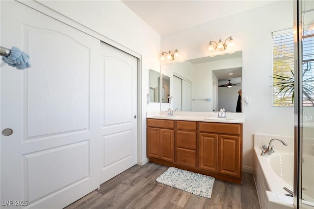 6121 Mission Gorge Ct, Las Vegas, NV 89130 - bathroom featuring double vanity, a garden tub, wood finished floors, and ceiling fan