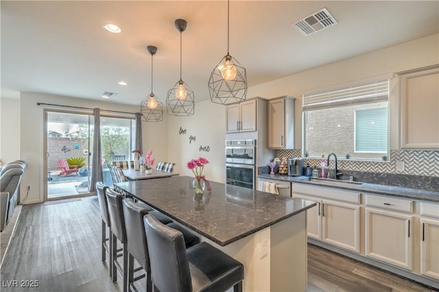10031 Fletcher Peak Ave, Las Vegas, NV 89178 - kitchen with a sink, stainless steel appliances, backsplash, a kitchen island, and dark wood-style flooring