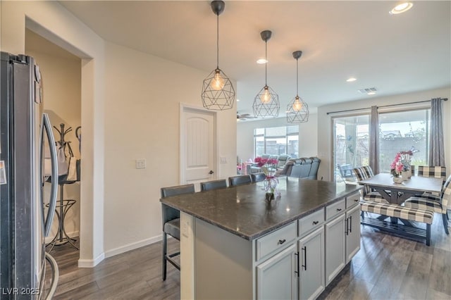 10031 Fletcher Peak Ave, Las Vegas, NV 89178 - kitchen with freestanding refrigerator, dark wood finished floors, a breakfast bar, a center island, and baseboards