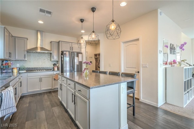 10031 Fletcher Peak Ave, Las Vegas, NV 89178 - kitchen featuring wall chimney range hood, freestanding refrigerator, a kitchen breakfast bar, dark wood finished floors, and black cooktop