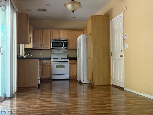 8708 Gateway Glen Dr, Las Vegas, NV 89178 - kitchen featuring white appliances, dark wood-style flooring, dark countertops, baseboards, and a sink