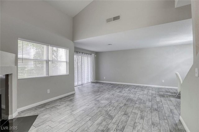 6250 W Flamingo Rd Unit 43, Las Vegas, NV 89103 - unfurnished living room featuring a fireplace, wood finished floors, high vaulted ceiling, and baseboards