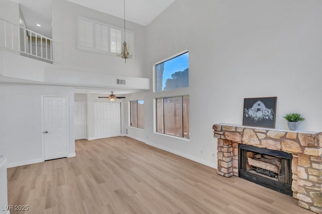 125 Firecreek Cir, Las Vegas, NV 89107 - unfurnished living room with a towering ceiling, a fireplace, wood finished floors, baseboards, and ceiling fan