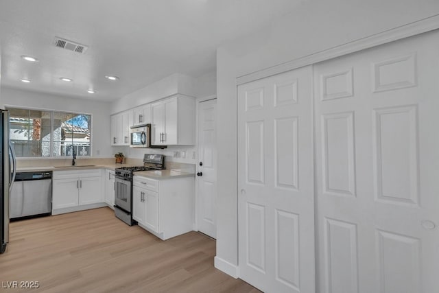 125 Firecreek Cir, Las Vegas, NV 89107 - kitchen featuring appliances with stainless steel finishes, a sink, white cabinets, light wood-style floors, and light countertops