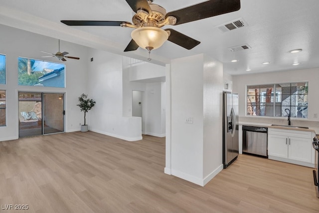 125 Firecreek Cir, Las Vegas, NV 89107 - kitchen featuring stainless steel appliances, a sink, white cabinets, light wood-type flooring, and a ceiling fan