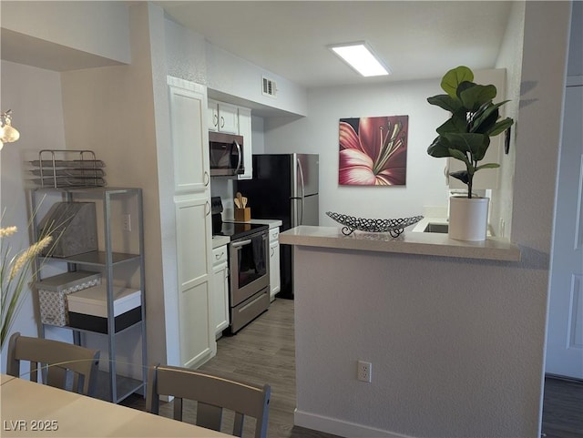 6650 W Warm Springs Rd Unit 2159, Las Vegas, NV 89118 - kitchen with appliances with stainless steel finishes, white cabinetry, dark wood-style floors, a peninsula, and light countertops
