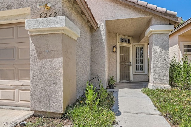 8242 Tribute Ln, Las Vegas, NV 89147 - view of exterior entry featuring a garage and stucco siding
