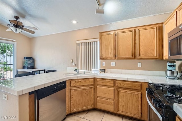 8242 Tribute Ln, Las Vegas, NV 89147 - kitchen with stainless steel appliances, a sink, a ceiling fan, a peninsula, and light tile patterned flooring