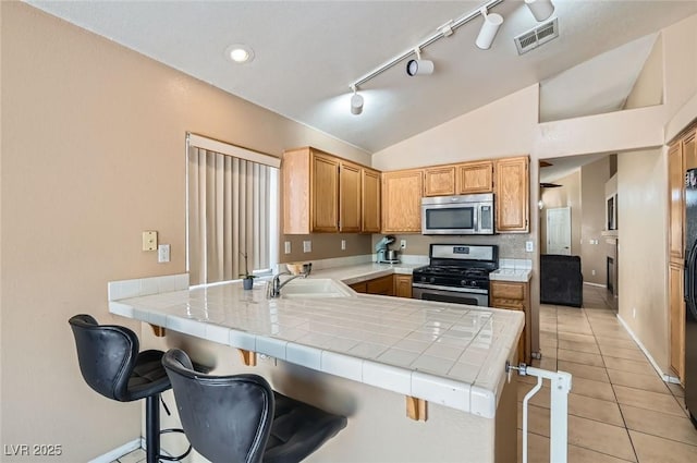 8242 Tribute Ln, Las Vegas, NV 89147 - kitchen with stainless steel appliances, a sink, tile counters, a peninsula, and light tile patterned flooring