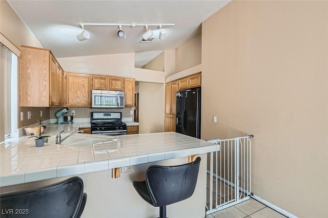 8242 Tribute Ln, Las Vegas, NV 89147 - kitchen featuring appliances with stainless steel finishes, track lighting, tile countertops, a peninsula, and lofted ceiling
