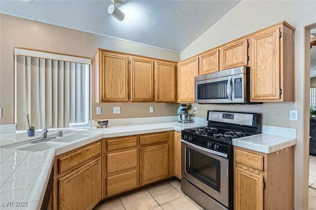 8242 Tribute Ln, Las Vegas, NV 89147 - kitchen with stainless steel appliances, vaulted ceiling, light tile patterned flooring, a sink, and a textured ceiling