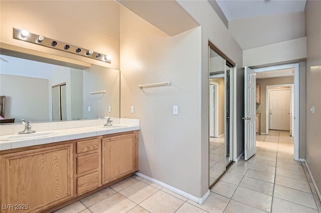 8242 Tribute Ln, Las Vegas, NV 89147 - full bath featuring double vanity, tile patterned floors, baseboards, and lofted ceiling