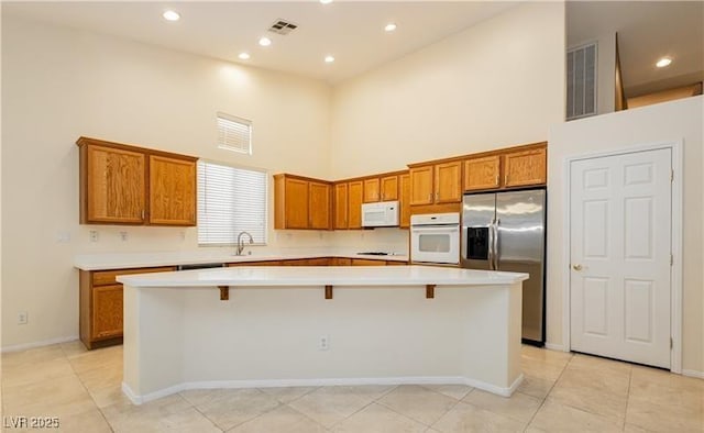 11204 Newbury Hills Ave, Las Vegas, NV 89138 - kitchen featuring white appliances, a high ceiling, brown cabinets, light countertops, and a center island
