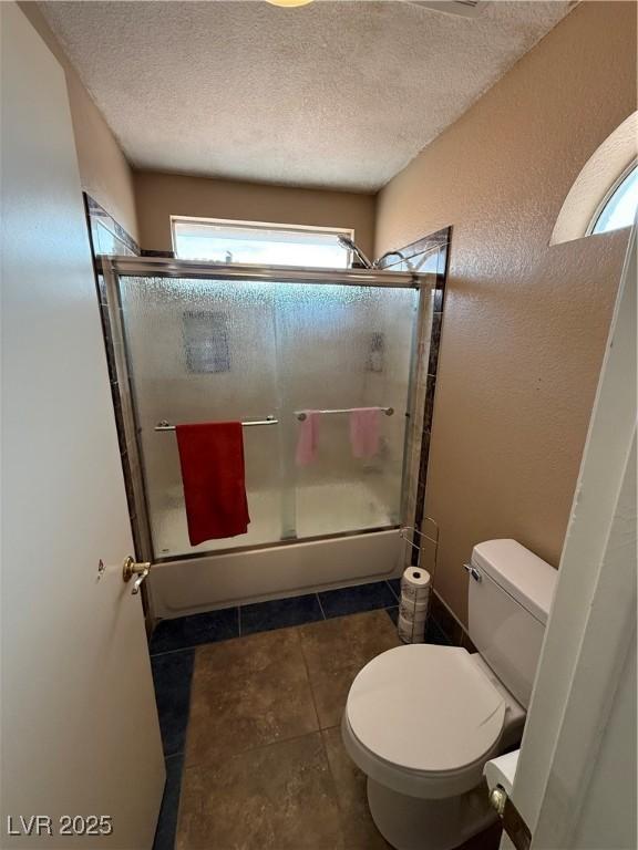 5517 Rock Creek Ln, Las Vegas, NV 89130 - bathroom with toilet, a textured ceiling, tile patterned flooring, a textured wall, and enclosed tub / shower combo