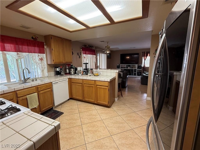 5517 Rock Creek Ln, Las Vegas, NV 89130 - kitchen with freestanding refrigerator, dishwasher, a peninsula, a sink, and tile counters