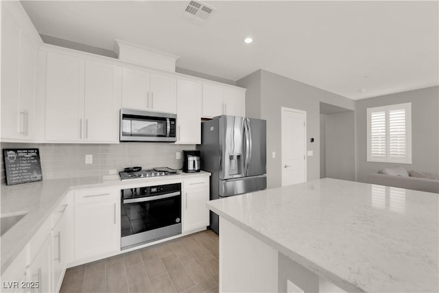 872 Pointe Arbor St, Henderson, NV 89011 - kitchen with appliances with stainless steel finishes, backsplash, light stone counters, white cabinetry, and recessed lighting